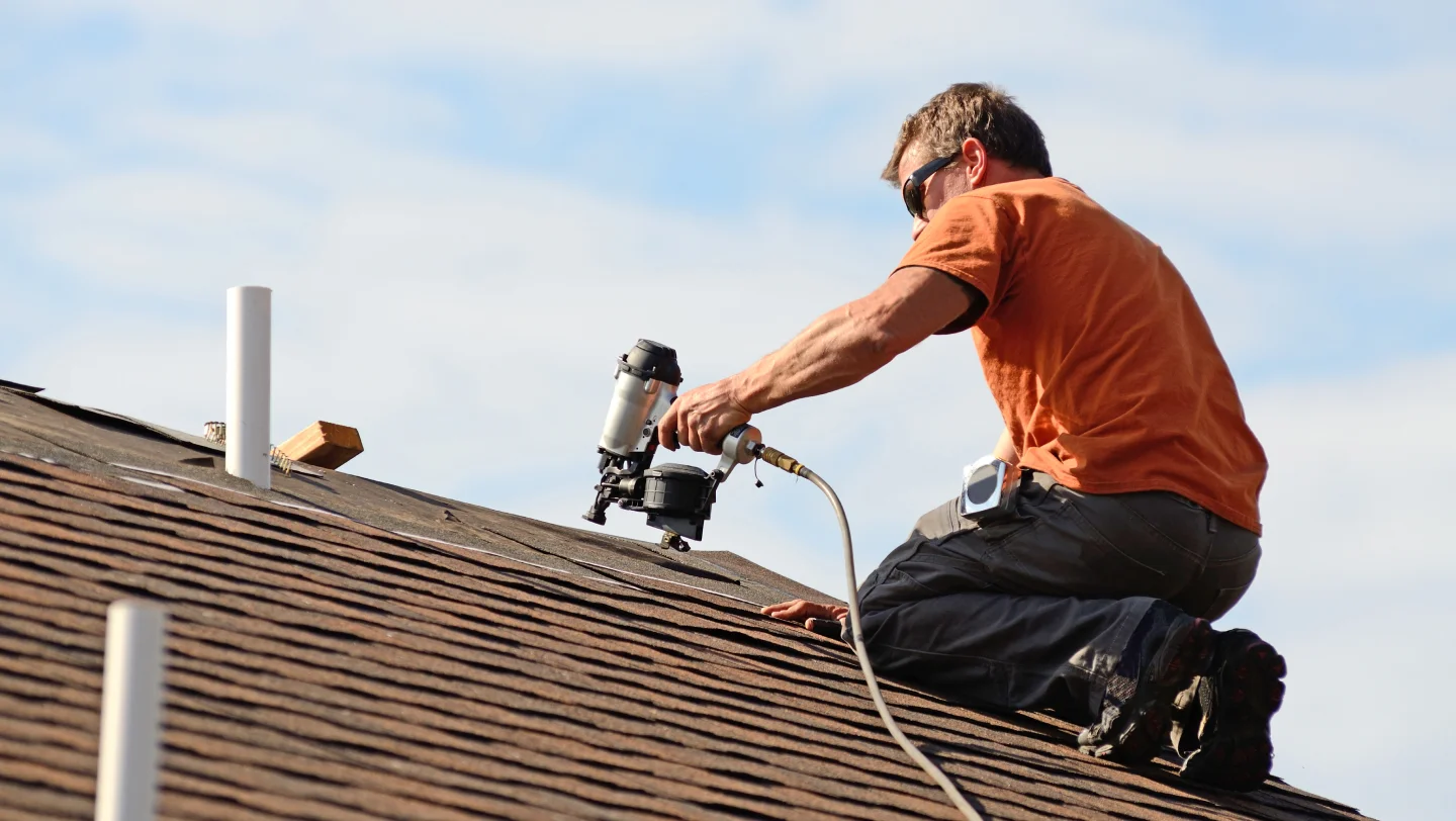 Roofer repairing shingles on a home